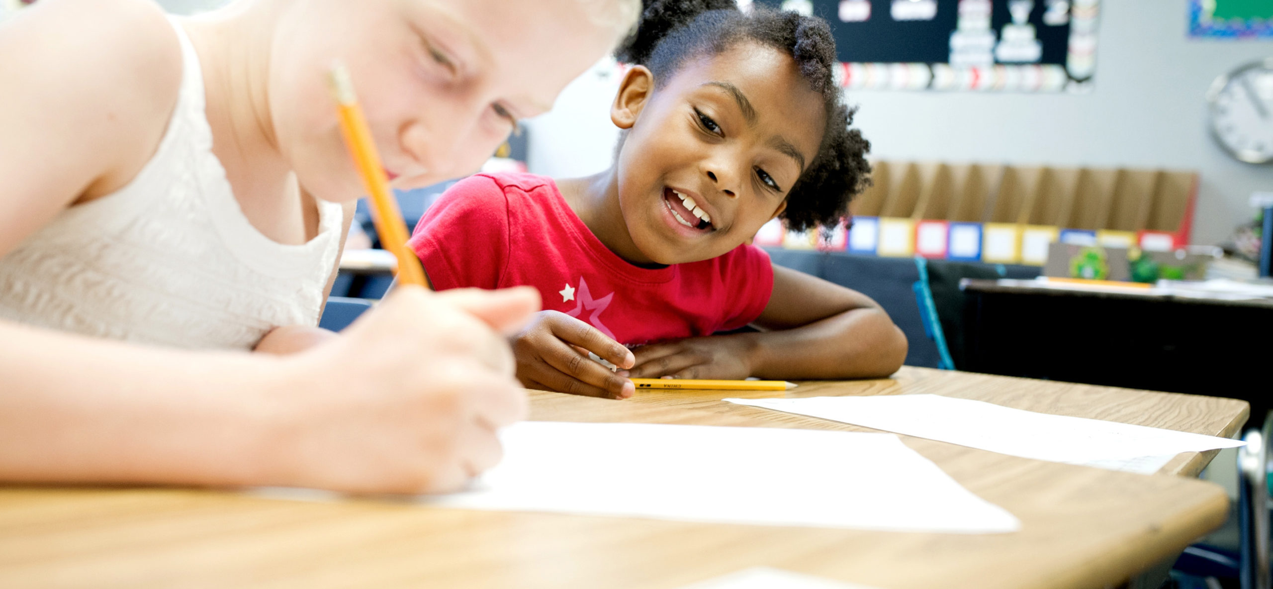 two girls working on a worksheet together at summer camp