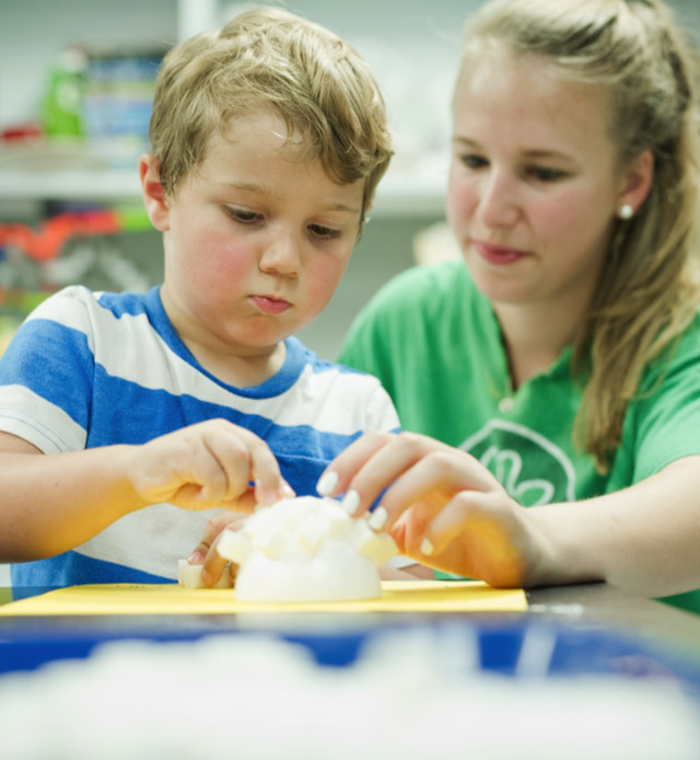 a camp counselor helping a little boy