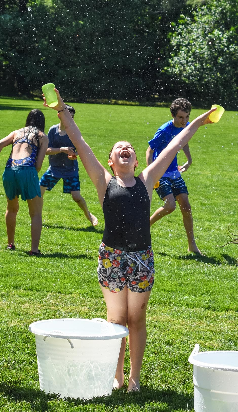 Girl with her arms in the air cheering at water games during Camp Mustang