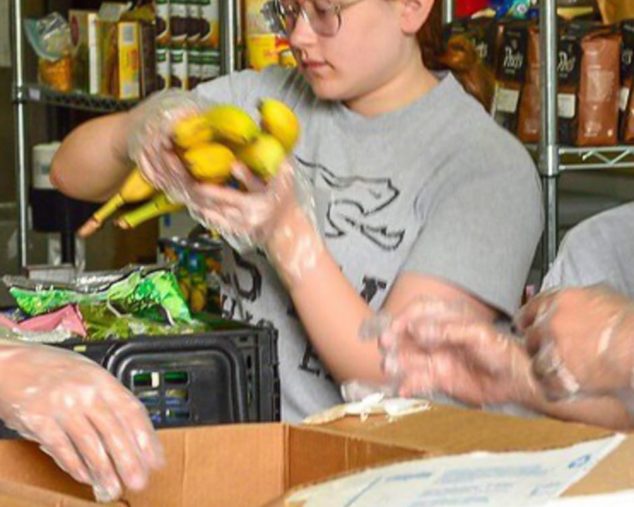 Girl sorting bananas and volunteering at a food bank for community service program