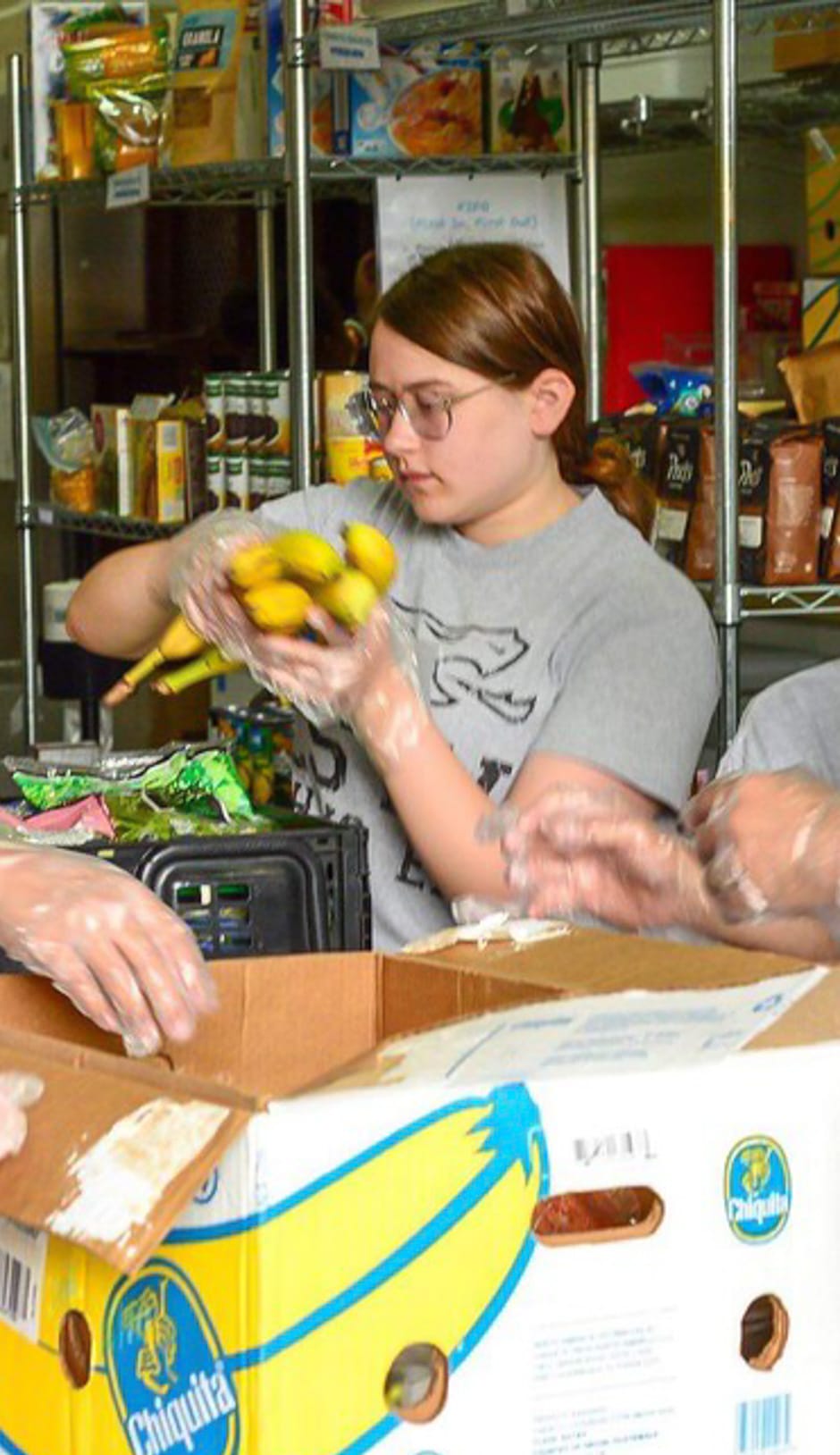 Girl sorting bananas and volunteering at a food bank for community service program