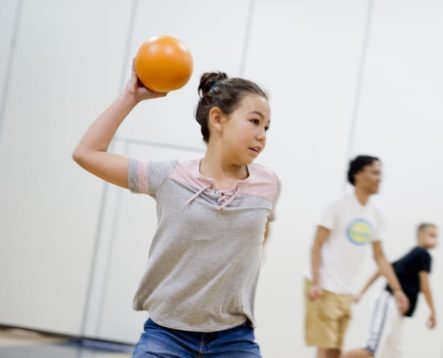 Girl throwing a dodgeball in the gym