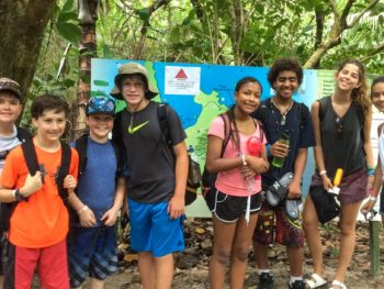 Group of kids standing in forest with hiking backpacks on