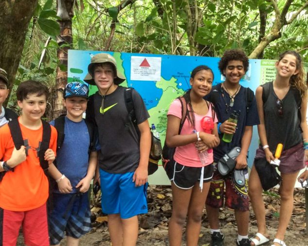 Group of kids standing in forest with hiking backpacks on