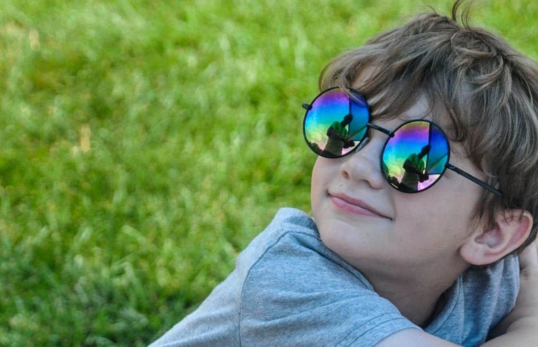 Young boy wearing sunglasses and sitting on the grass