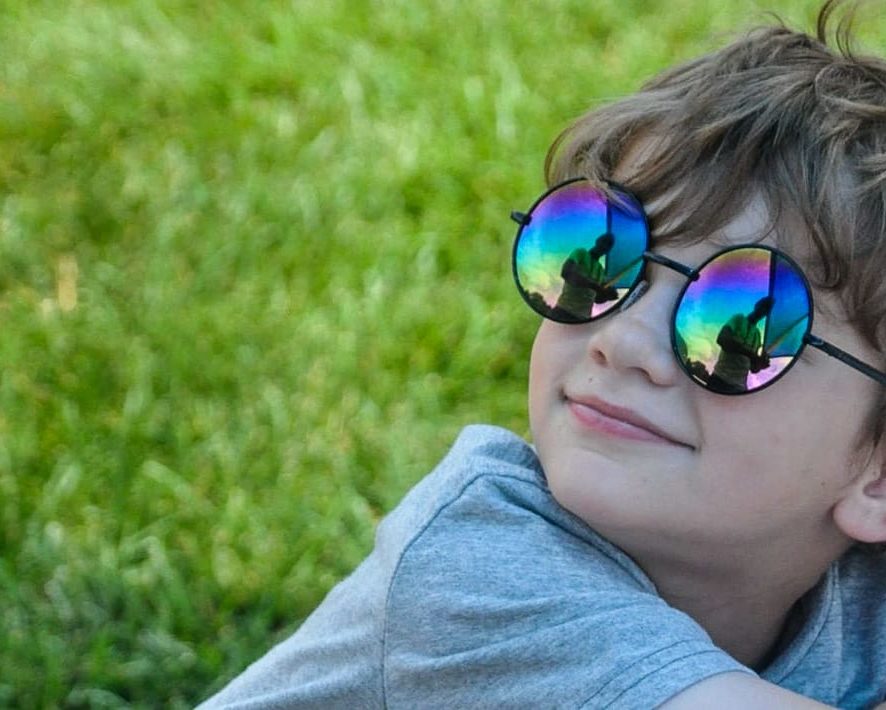 Young boy wearing sunglasses and sitting on the grass