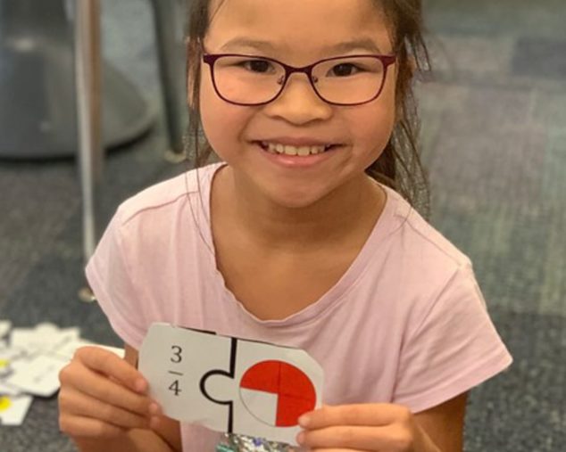 Young female holding ratio cards for algebra program