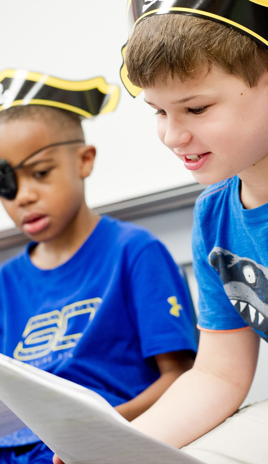 Two boys wearing pirate hats and eye patches reading