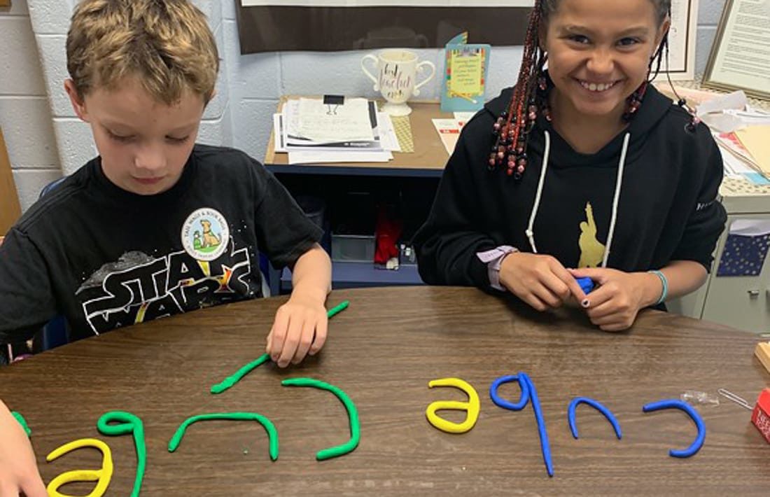 Two students using clay letters to spell words