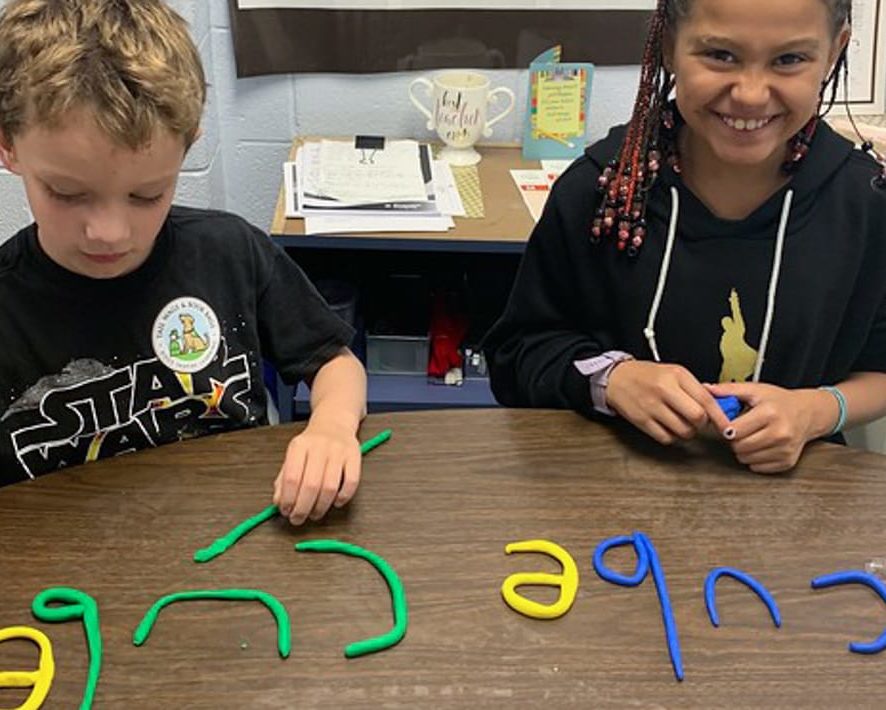 Two students using clay letters to spell words