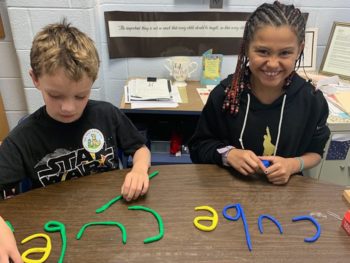 Two students using clay letters to spell words