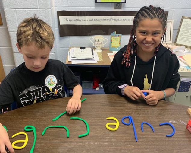 Two students using clay letters to spell words
