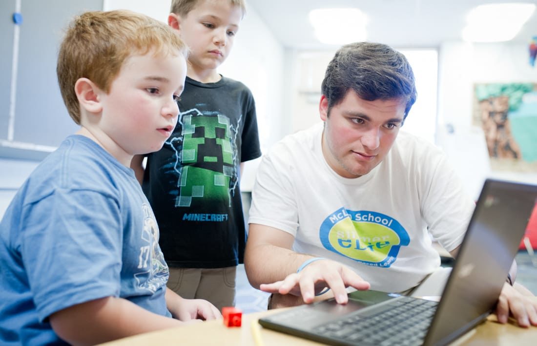 Staff and boys learning writing techniques on the computer