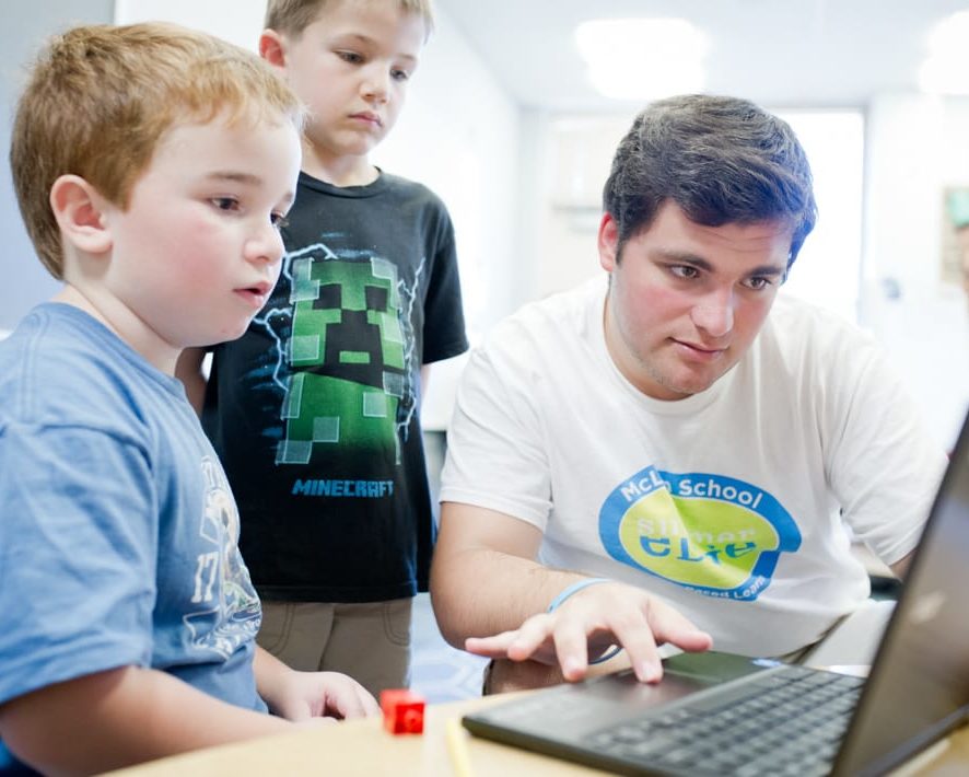 Staff and boys learning writing techniques on the computer