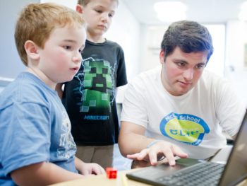 Staff and boys learning writing techniques on the computer