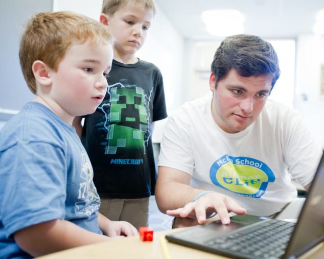 Staff and boys learning writing techniques on the computer