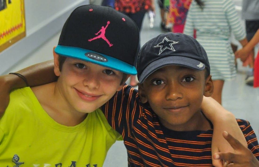 Two boys with arms around each other smiling