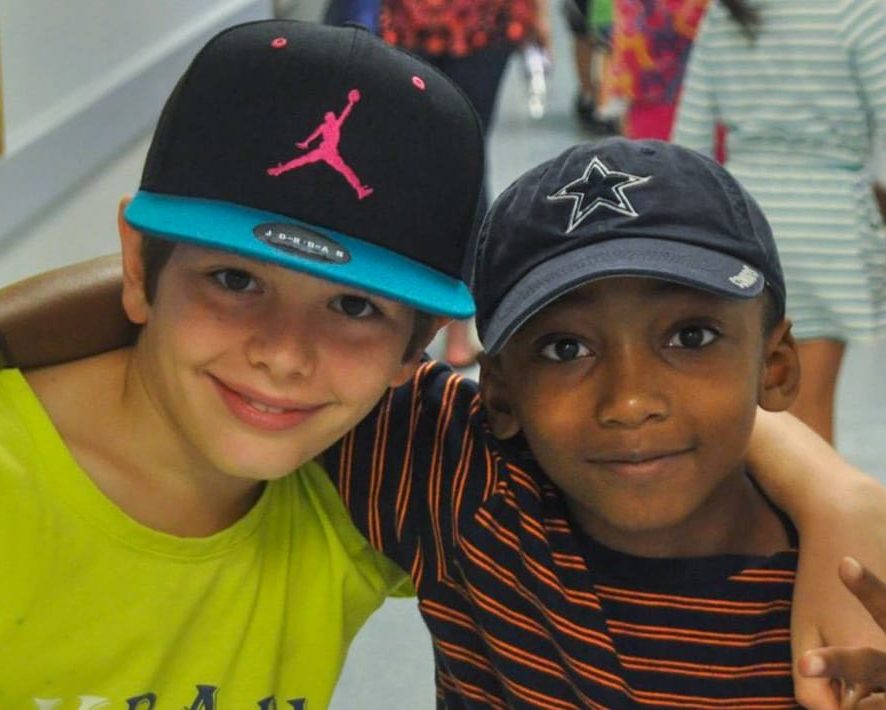 Two boys with arms around each other smiling