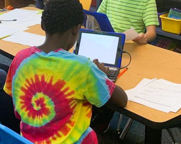 Boys sitting at a table with iPad during the Master Mind program