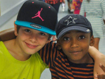 Two boys with arms around each other smiling