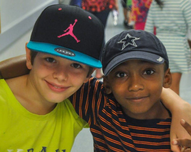 Two boys with arms around each other smiling