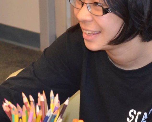 Student at Middle School Reading with colored pencils in front