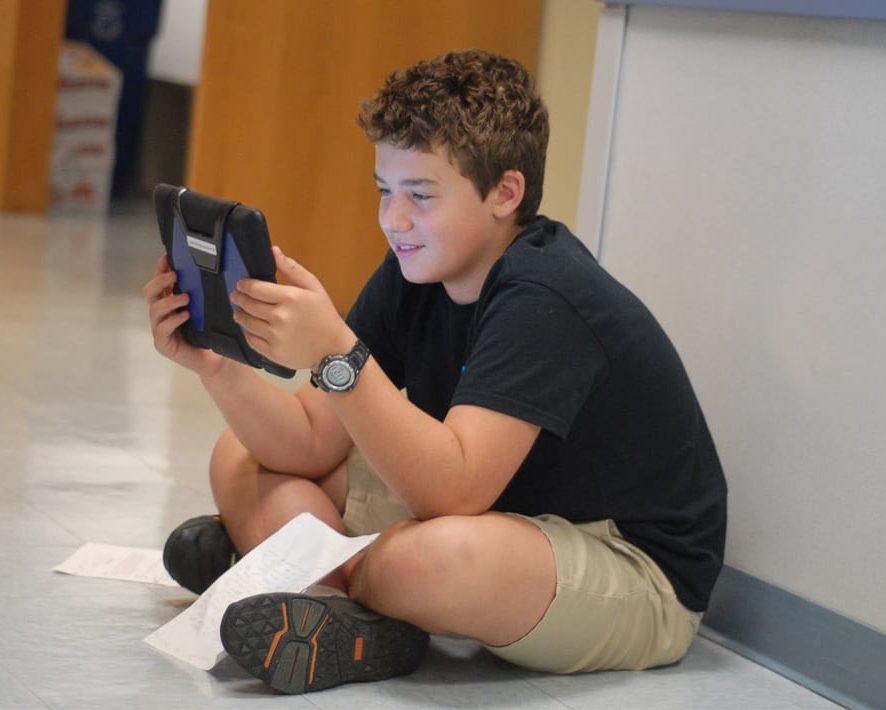 Middle school student in hallway practicing his writing