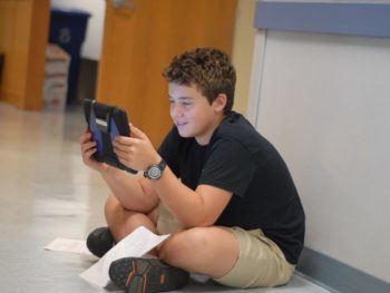 Middle school student in hallway practicing his writing