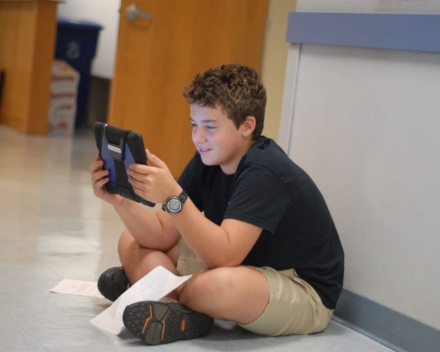 Middle school student in hallway practicing his writing