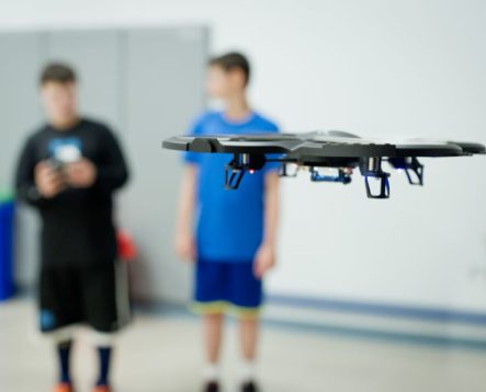 Two campers flying a drone in a classroom