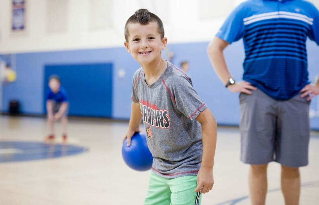 Boy holding a dodgeball in the gym