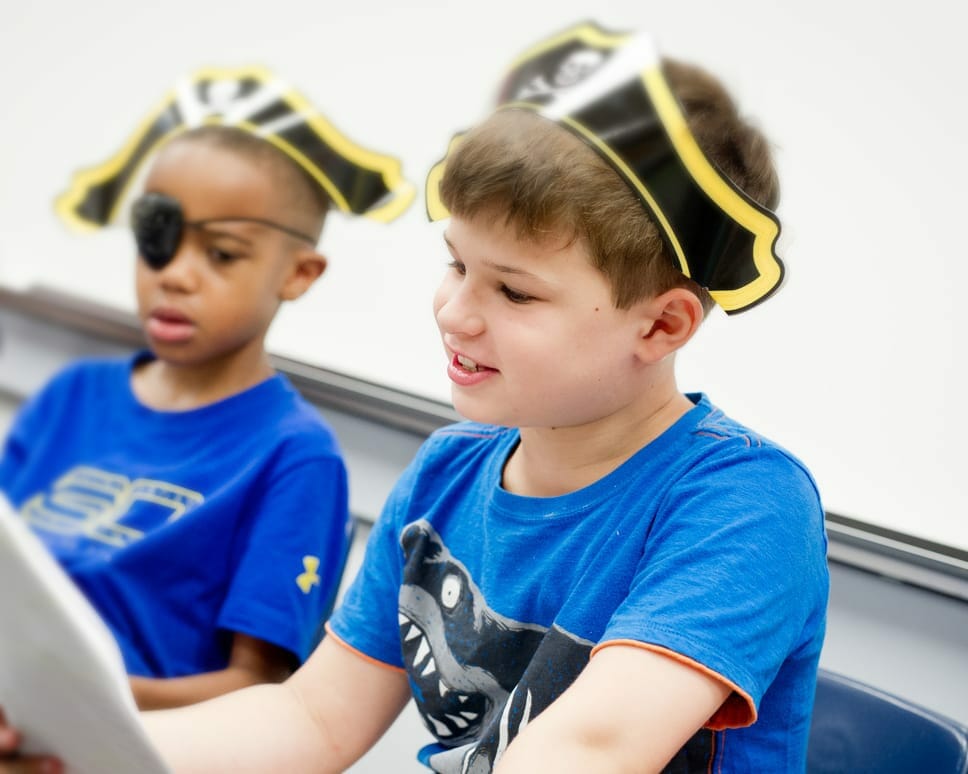 Two boys wearing pirate hats and eye patches reading