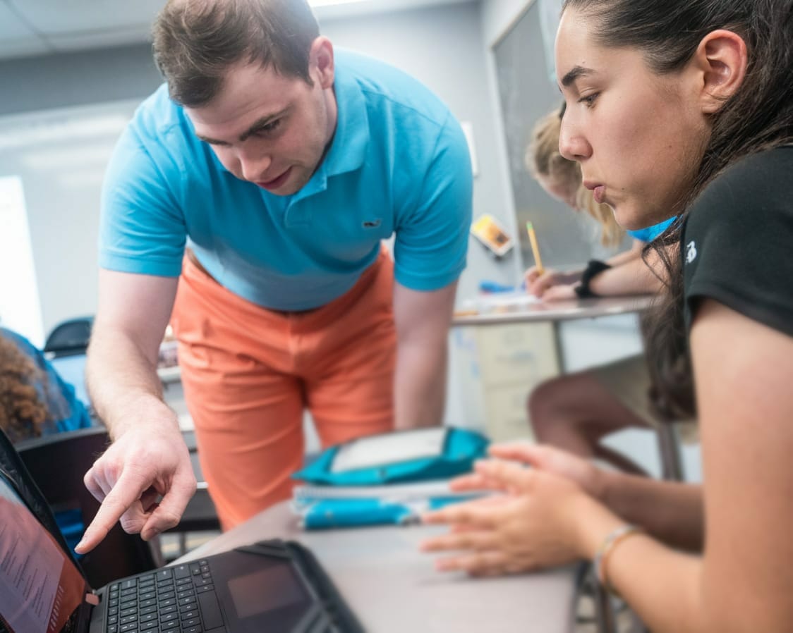 Teacher pointing to a computer