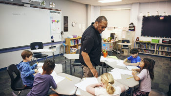 A teacher and a group of students in a classroom.