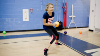 Girl throwing a dodgeball in the gym