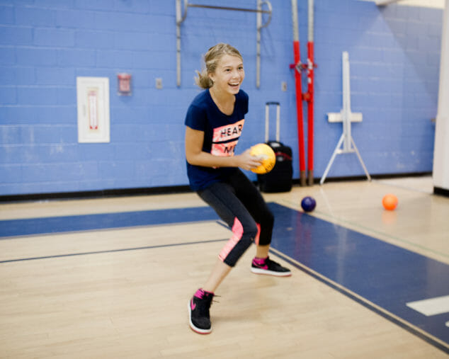 Girl throwing a dodgeball in the gym