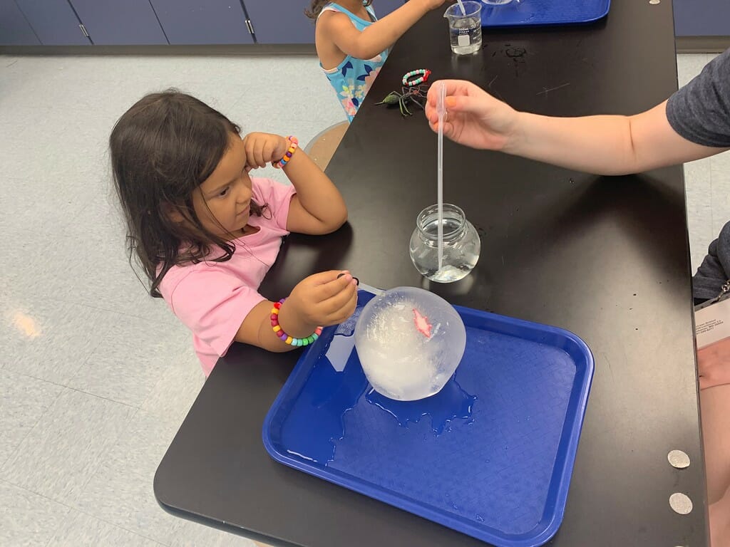 A little girl working to melt ice.